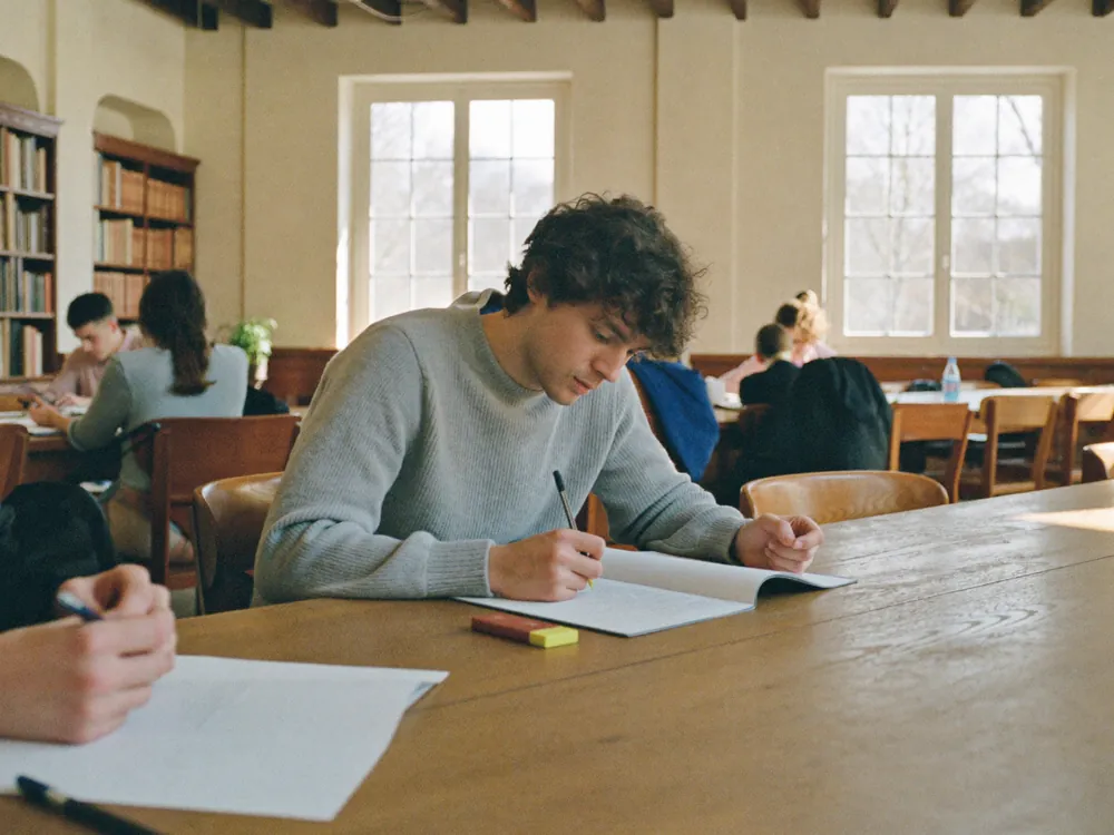 Un ragazzo concentrato studia in biblioteca