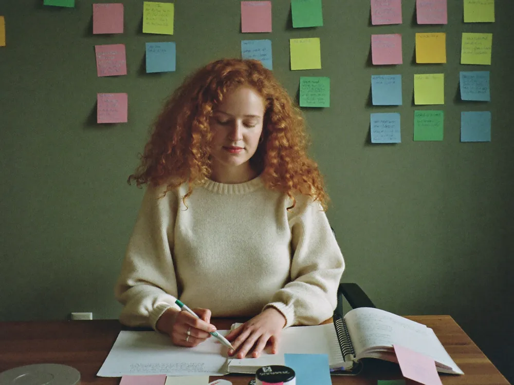 Una ragazza alla scrivania organizza la settimana con foglietti colorati
